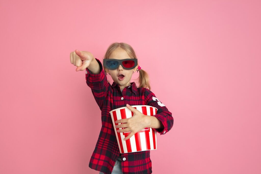 Petite fille avec ses popcorn et ses lunettes 3D sur fond rose - crédit photo Freepik